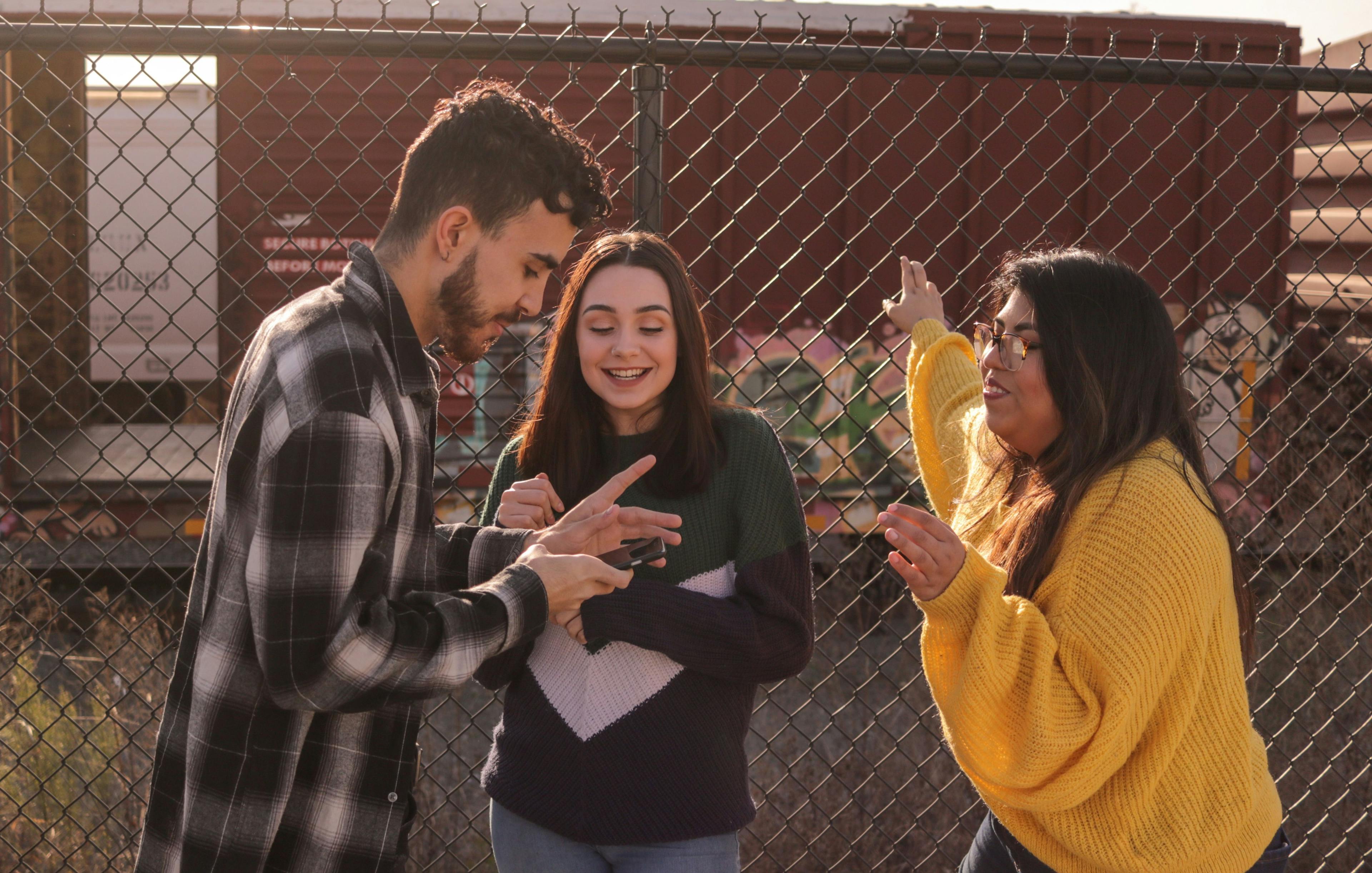 Bilde av tre unge mennesker som ler og ser på mobilen